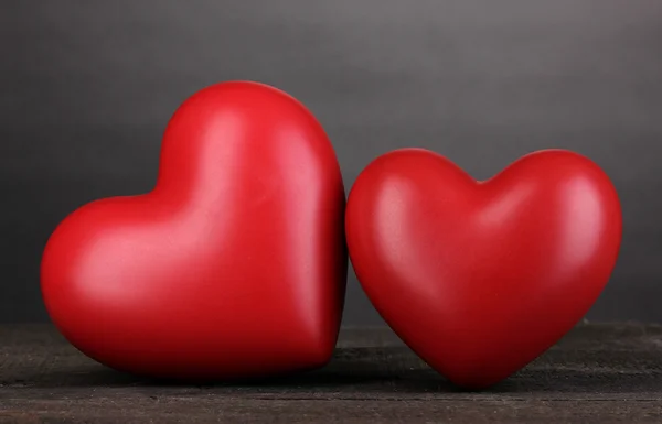 Gri arkaplanda tahta masada iki dekoratif kırmızı kalp. — Stok fotoğraf