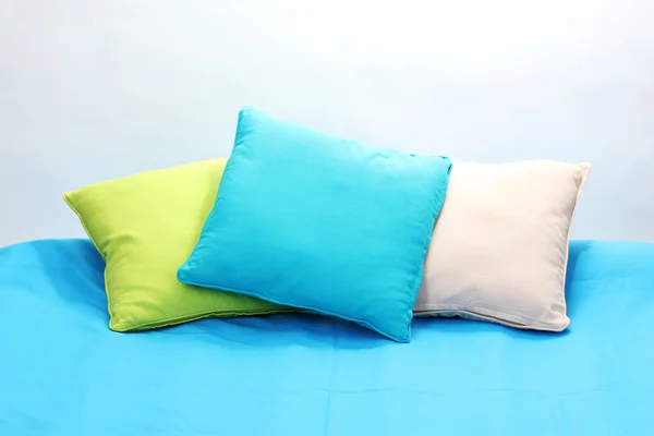 Almofadas brilhantes na cama no fundo branco — Fotografia de Stock