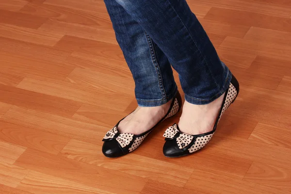 Benen in jeans en ballet platte schoenen op houten achtergrond — Stockfoto