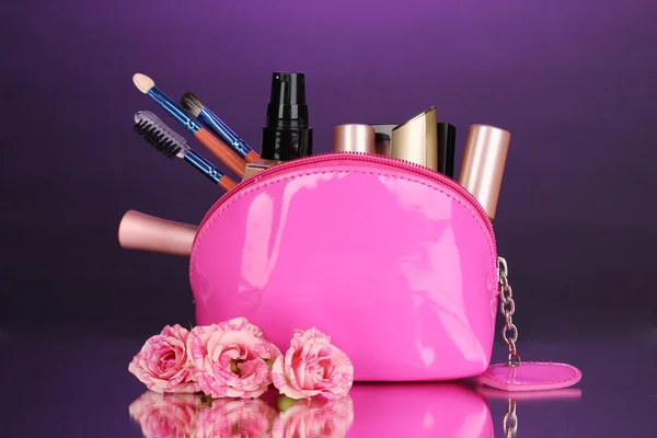 Макияж мешок с косметикой и щетки на фиолетовом фоне — стоковое фото
