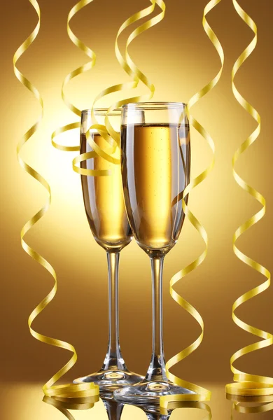 Gläser Champagner und Luftschlange auf gelbem Hintergrund — Stockfoto