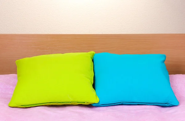 Helle Kissen auf dem Bett auf beigem Hintergrund — Stockfoto