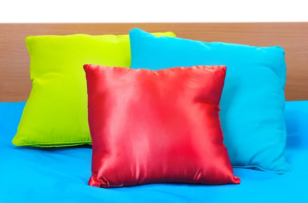 Almohadas brillantes en la cama sobre fondo blanco —  Fotos de Stock