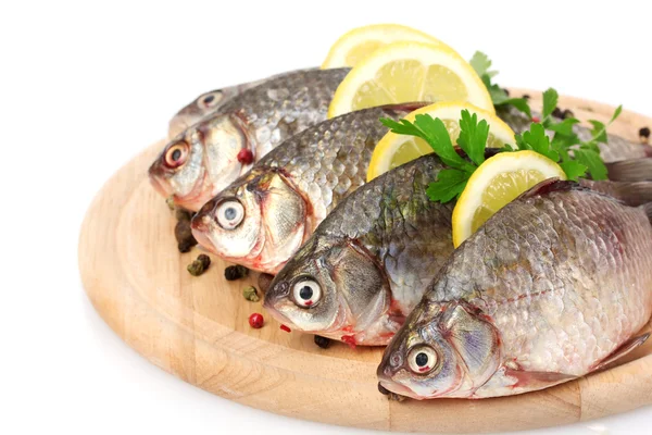 Fresh fishes with lemon, parsley and spice on wooden cutting board isolated on white — Stock Photo, Image