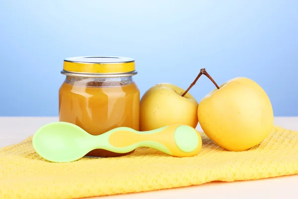 Jar of baby puree with spoon on napkin on blue background — Stock Photo, Image