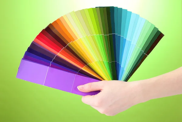 Χέρι που κρατά φωτεινή παλέτα των χρωμάτων σε πράσινο φόντο — 图库照片
