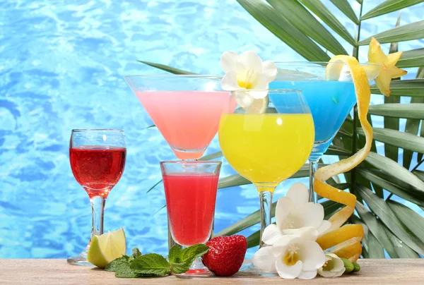 Exotické koktejly a květiny na stole na pozadí modré moře — Stock fotografie