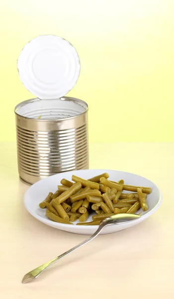 打开锡罐和板与法国豆和绿色背景上的木桌上的勺子 — 图库照片