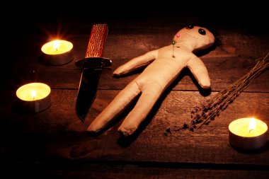 Voodoo doll boy on a wooden table in the candlelight clipart