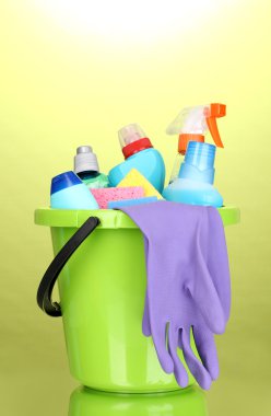 Bucket with cleaning items on green background clipart