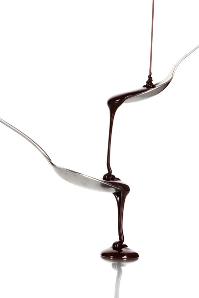 Schokolade in einen Löffel gegossen und von ihm zu einem anderen Löffel isoliert auf weiß — Stockfoto