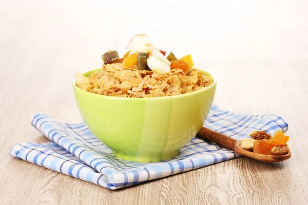 Leckere Cornflakes in Schüssel mit getrockneten Früchten auf Holztisch — Stockfoto