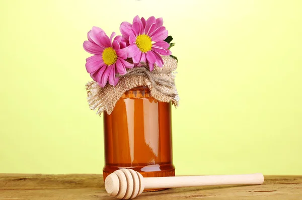 Dulce miel en tarro con rociador sobre mesa de madera sobre fondo verde —  Fotos de Stock
