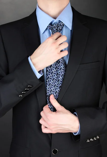 Hombre de negocios corrigiendo una corbata sobre fondo negro —  Fotos de Stock