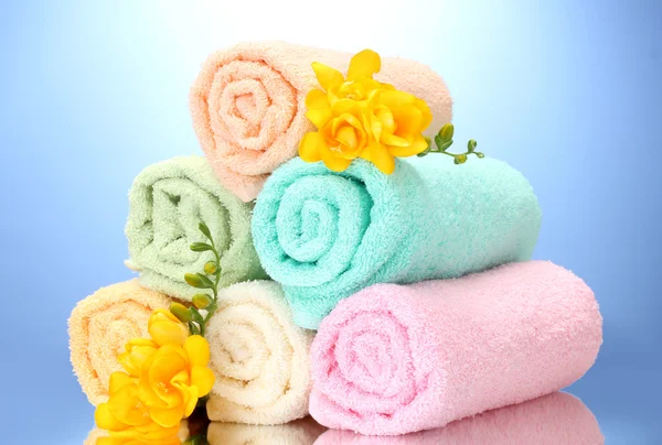 Barevné ručníky a květiny na modrém pozadí — Stock fotografie
