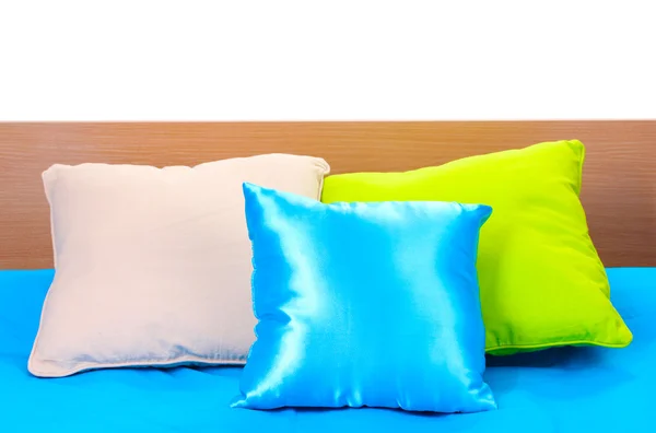Cuscini luminosi sul letto su sfondo bianco — Foto Stock