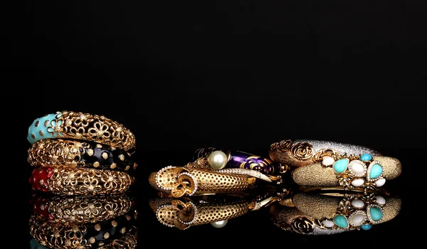 Schöne goldene Armbänder isoliert auf schwarzem Hintergrund — Stockfoto