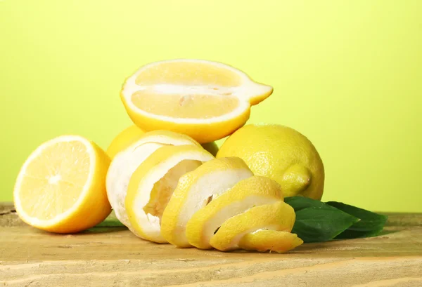 Rijp citroenen met bladeren op houten tafel op groene achtergrond — Stockfoto