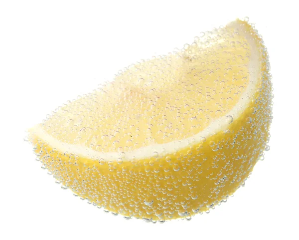 Кусок лимона в воде с пузырьками — стоковое фото