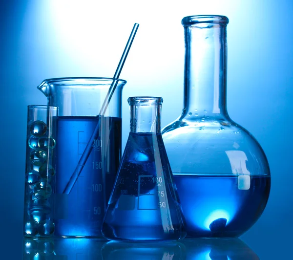 Тестові труби з синьою рідиною на синьому фоні — стокове фото