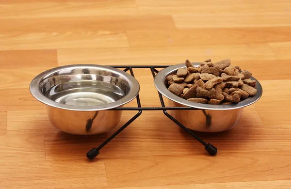 Suchý pes potravin a vody v kovové misky na podlaze — Stock fotografie