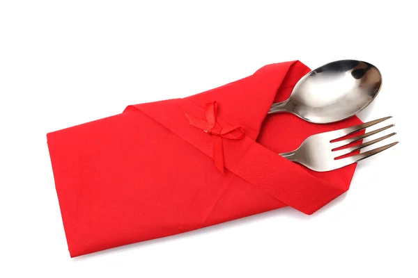 Garfo e colher em um pano vermelho com um arco isolado no branco — Fotografia de Stock