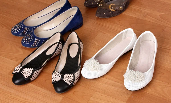 Several pairs of female flat shoes on wooden background — Stock Photo, Image