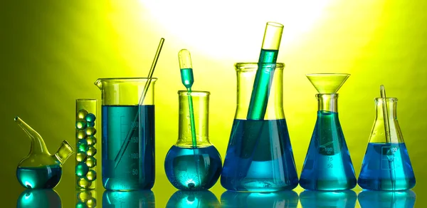Test-tubes with blue liquid on green background — Stock Photo, Image