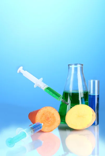 Injection into fresh vegetables on blue background — Stock Photo, Image