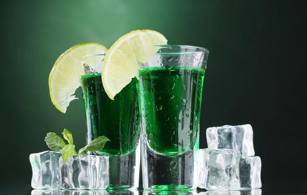 Dvě sklenice absintu, vápna a ledu na zeleném pozadí — Stock fotografie