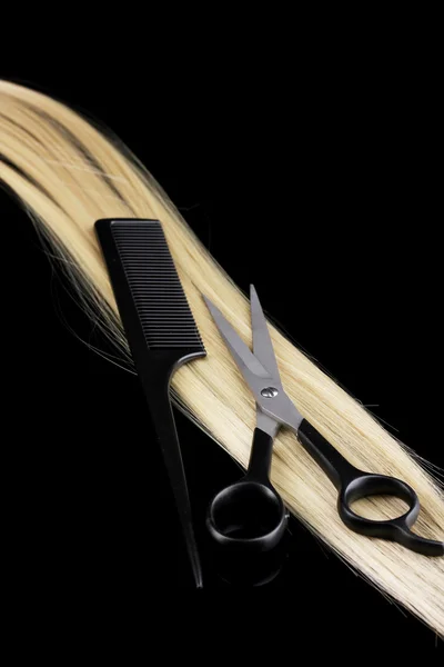 Cabelo loiro brilhante com tesouras de corte de cabelo e pente isolado em preto — Fotografia de Stock