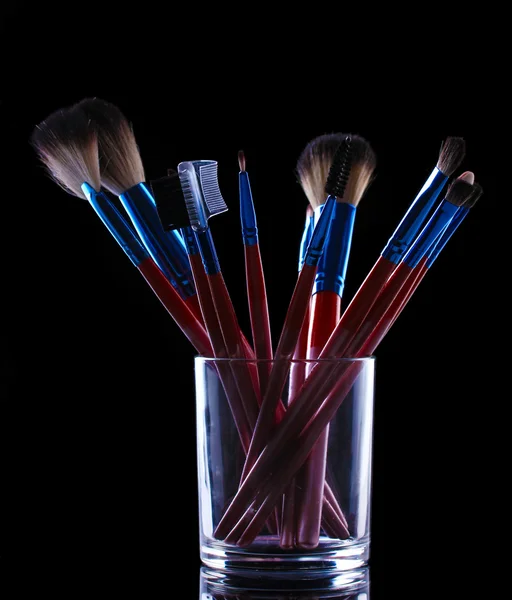 Pincéis de maquiagem em copo de vidro no fundo cinza — Fotografia de Stock