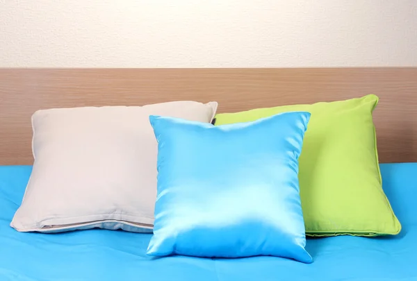 Ljusa kuddar på sängen på beige bakgrund — Stockfoto