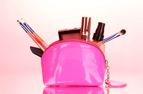 Bolsa de maquillaje con cosméticos y pinceles sobre fondo rosa —  Fotos de Stock