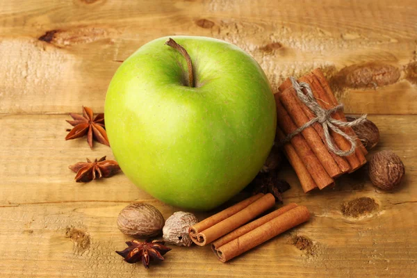 Laski cynamonu, zielone jabłko, gałka muszkatołowa, anyż na drewnianym stole — Zdjęcie stockowe