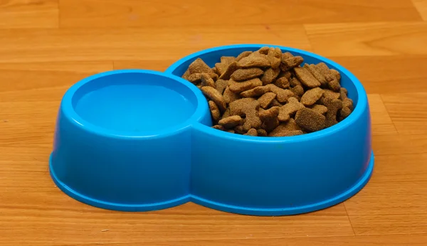 Сухой корм для собак и вода в голубой миске на полу — стоковое фото