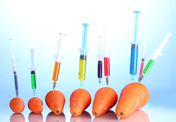 Injection into fresh carrot on blue background — Zdjęcie stockowe