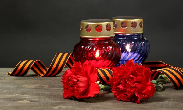 Μνήμη φανάρι με κεριά, Κόκκινα γαρίφαλα και κορδέλα του Αγίου Γεωργίου στο ξύλινο τραπέζι σε γκρι φόντο — Φωτογραφία Αρχείου