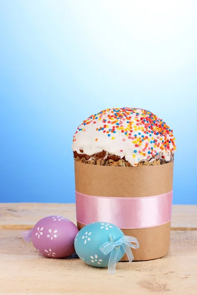 Vackra påsk kaka med ägg på träbord på blå bakgrund — Stockfoto