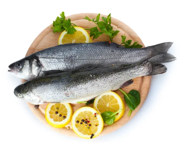 Verse vissen met citroen, peterselie en kruiden op houten snijplank geïsoleerd op wit — Stockfoto