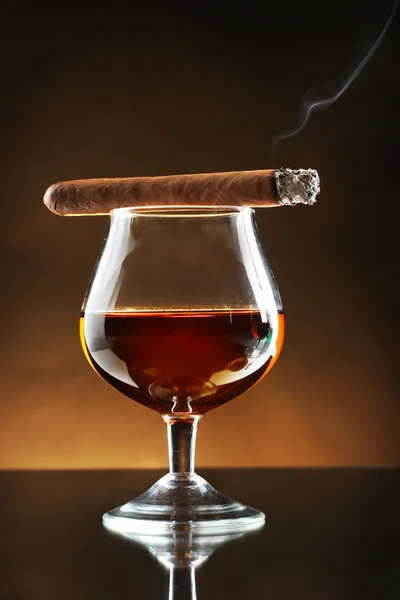 Bicchiere di brandy e sigaro su sfondo marrone — Foto Stock