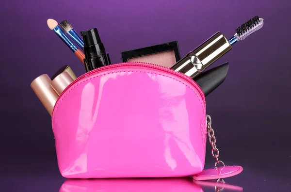 Макияж мешок с косметикой и щетки на фиолетовом фоне — стоковое фото