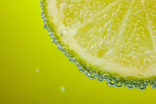 Slice of lemon in the water with bubbles — Stock Photo, Image
