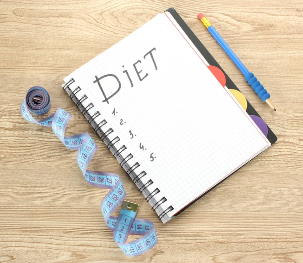 Planning of diet. Notebook measuring tape and pen on wooden table — Stock Photo, Image