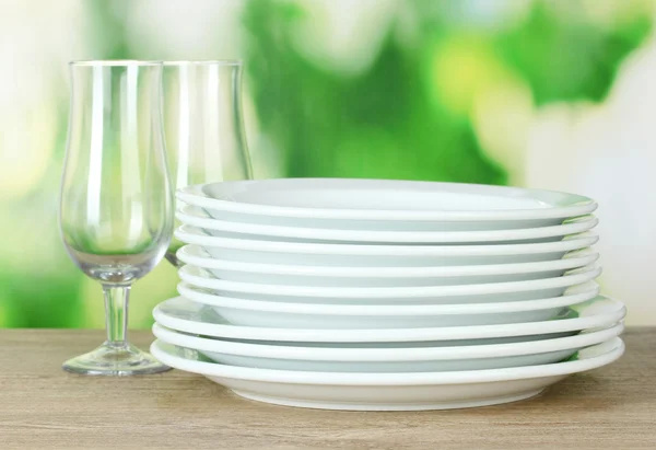 Чистые блюда на деревянном столе на зеленом фоне — стоковое фото