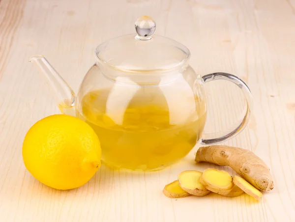 Healthy ginger tea in kettle with lemon on wooden background — Stock Photo, Image