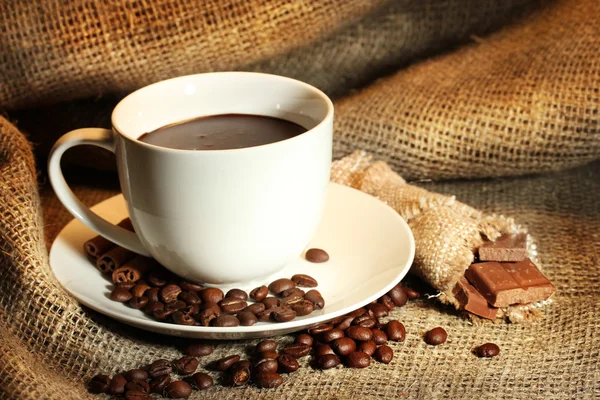 Kopje koffie, bonen en chocolade op plundering achtergrond — Stockfoto