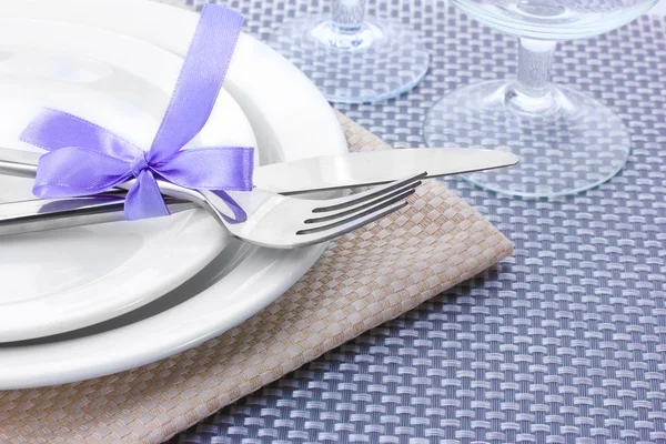白空盘子、 叉子和刀绑丝带和灰色的桌布上的眼镜 — 图库照片
