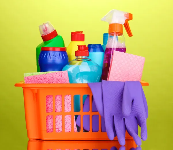 Basket with cleaning items on green background — Stock Photo, Image