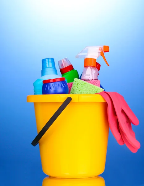 Bucket with cleaning items on blue background — Stock Photo, Image